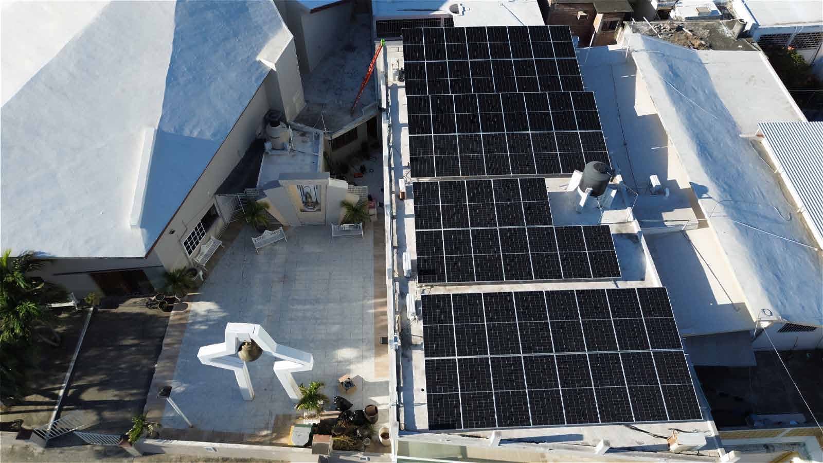 Vista aérea de una azotea con tres bloques de paneles solares instalados sobre la losa.
